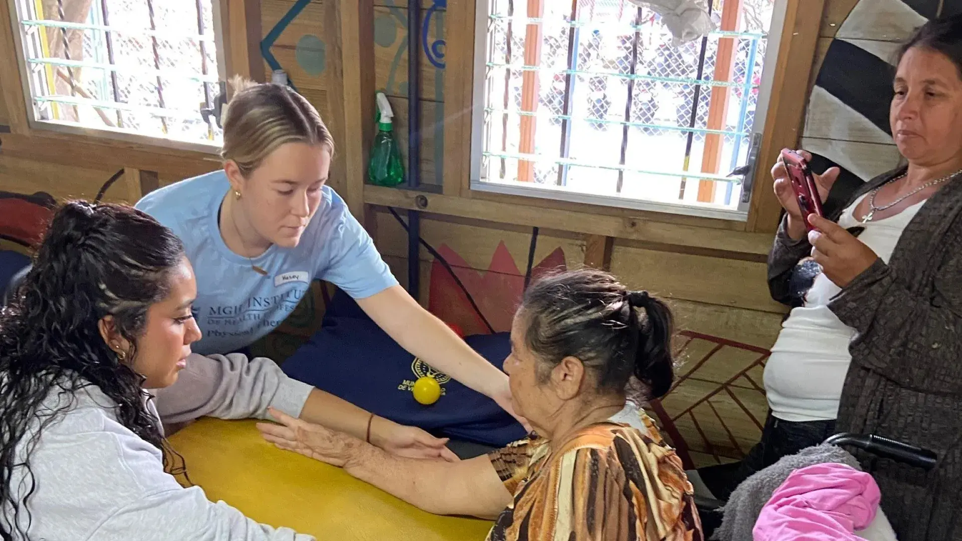two women help another who is in a wheelchair 