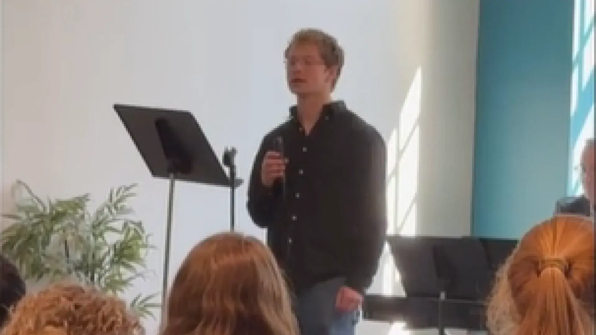 A man holds a microphone while people look on