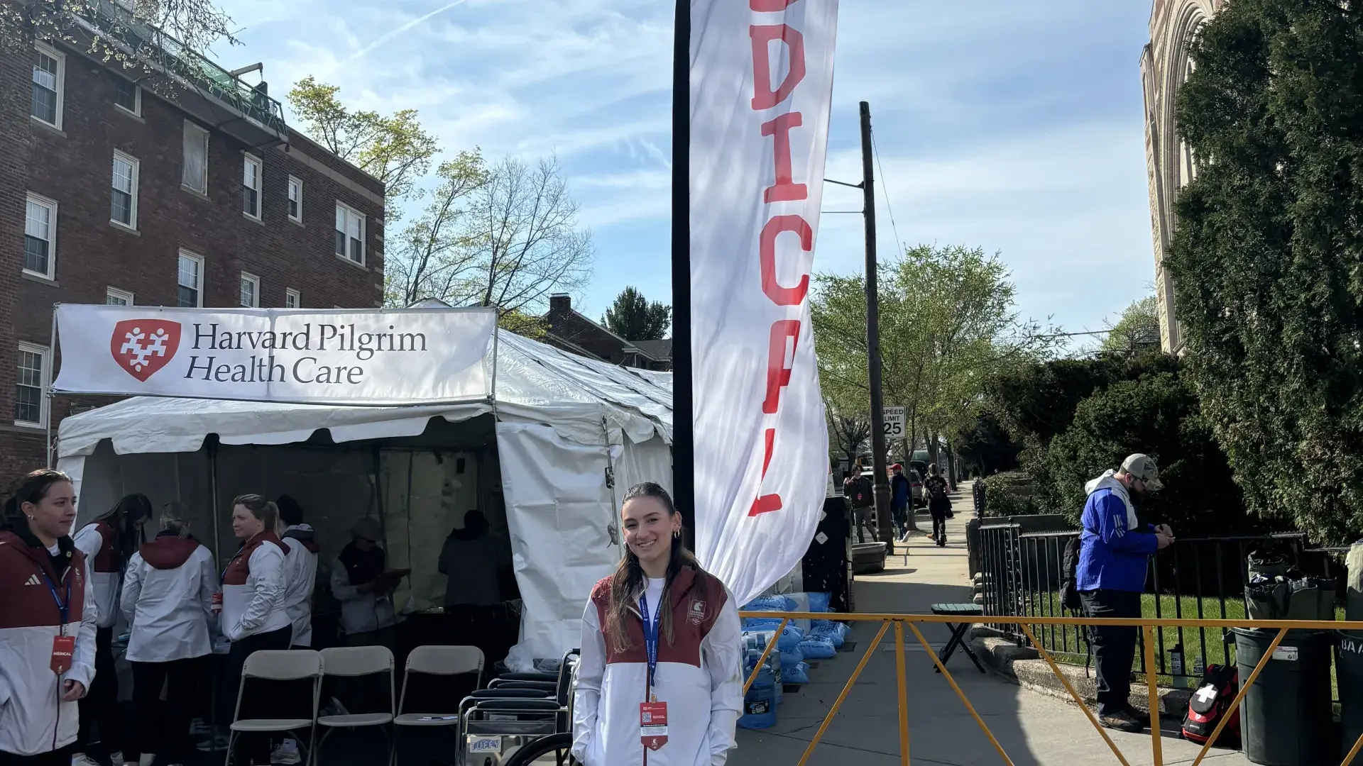 A woman stands in front of a tall flag that says medica