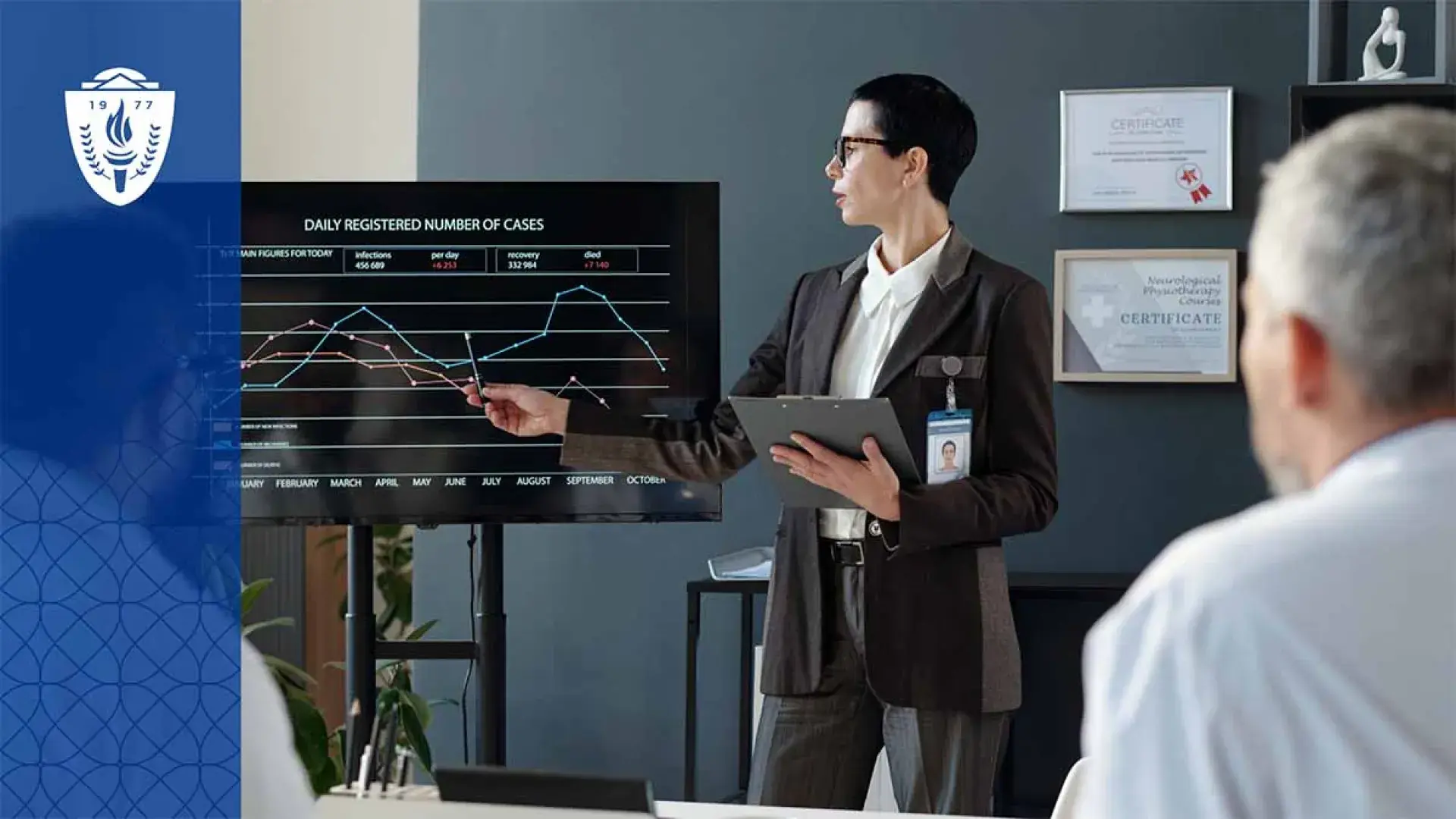Man presenting at front of room pointing at graph