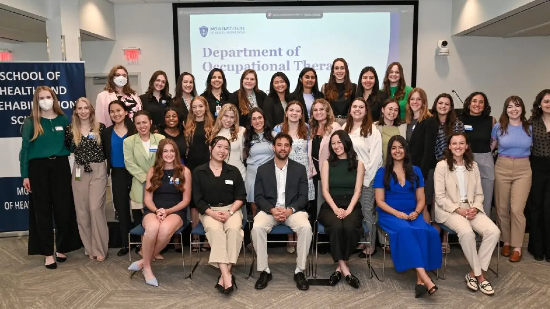 A group of people sit in rows in front of a screen that says Department of Occupational Therapy