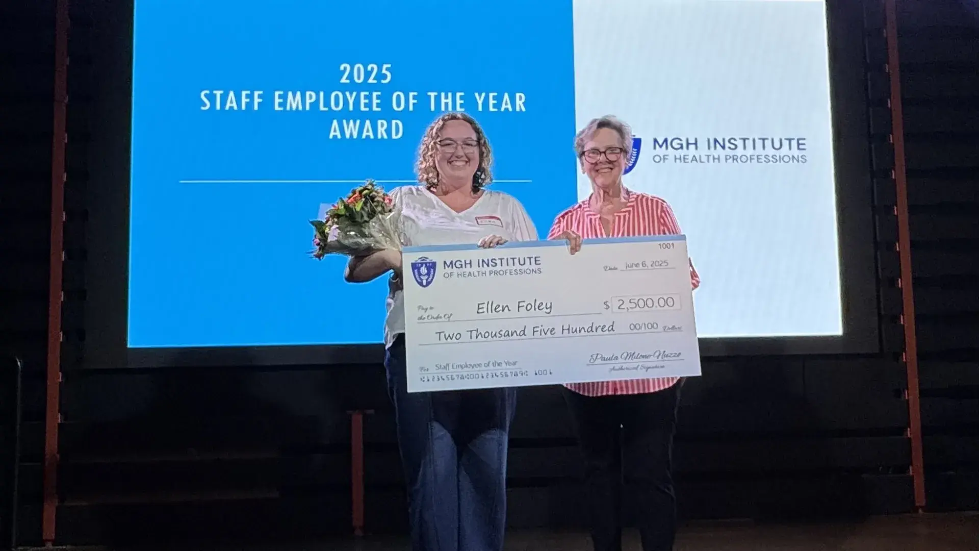 A photo of two women on a stage holding a check.