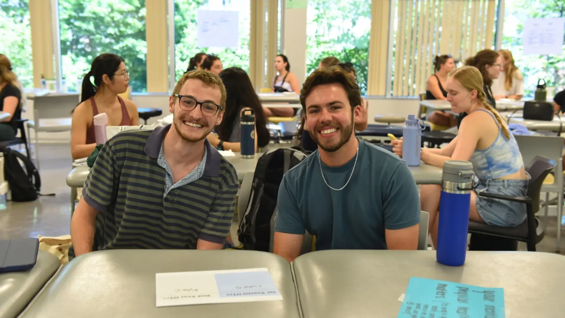 A photo of two men sitting in a classroom. 