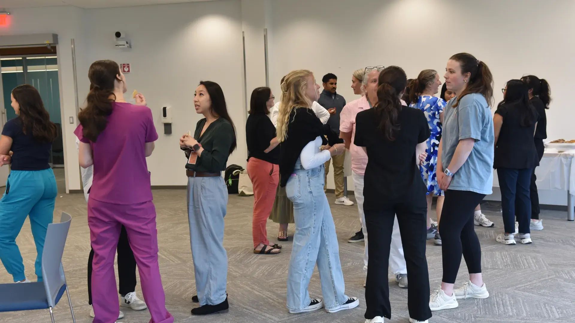 Small groups of people stand in a room conversing with each other