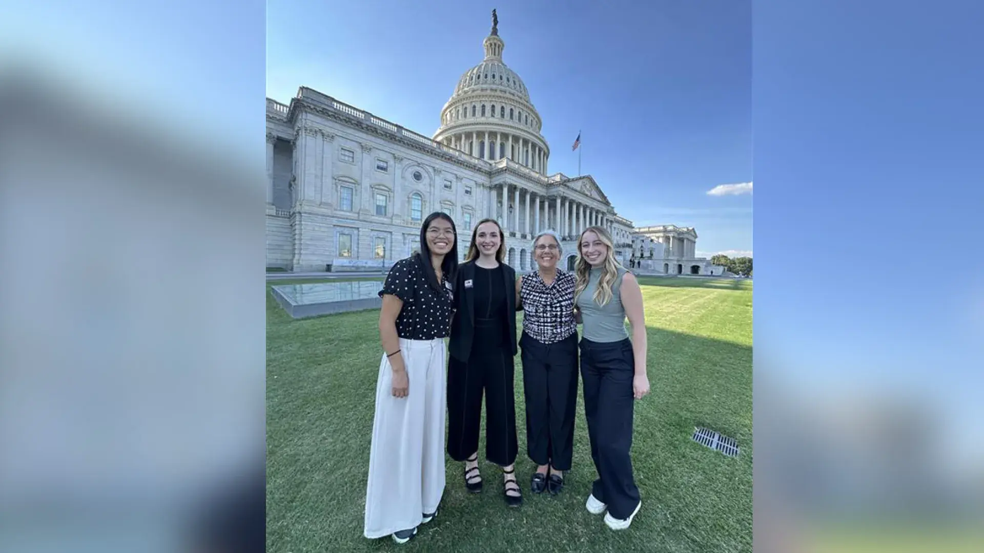 Four people pose with the US Capitol in the background