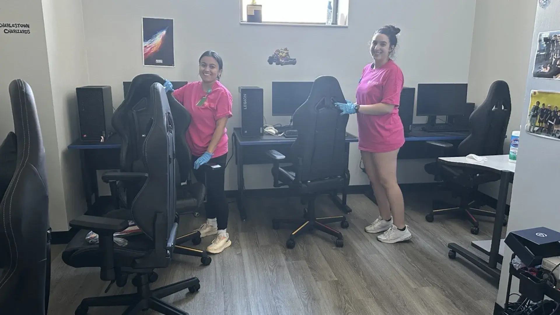 Two women cleaning a room with desks chairs and computers