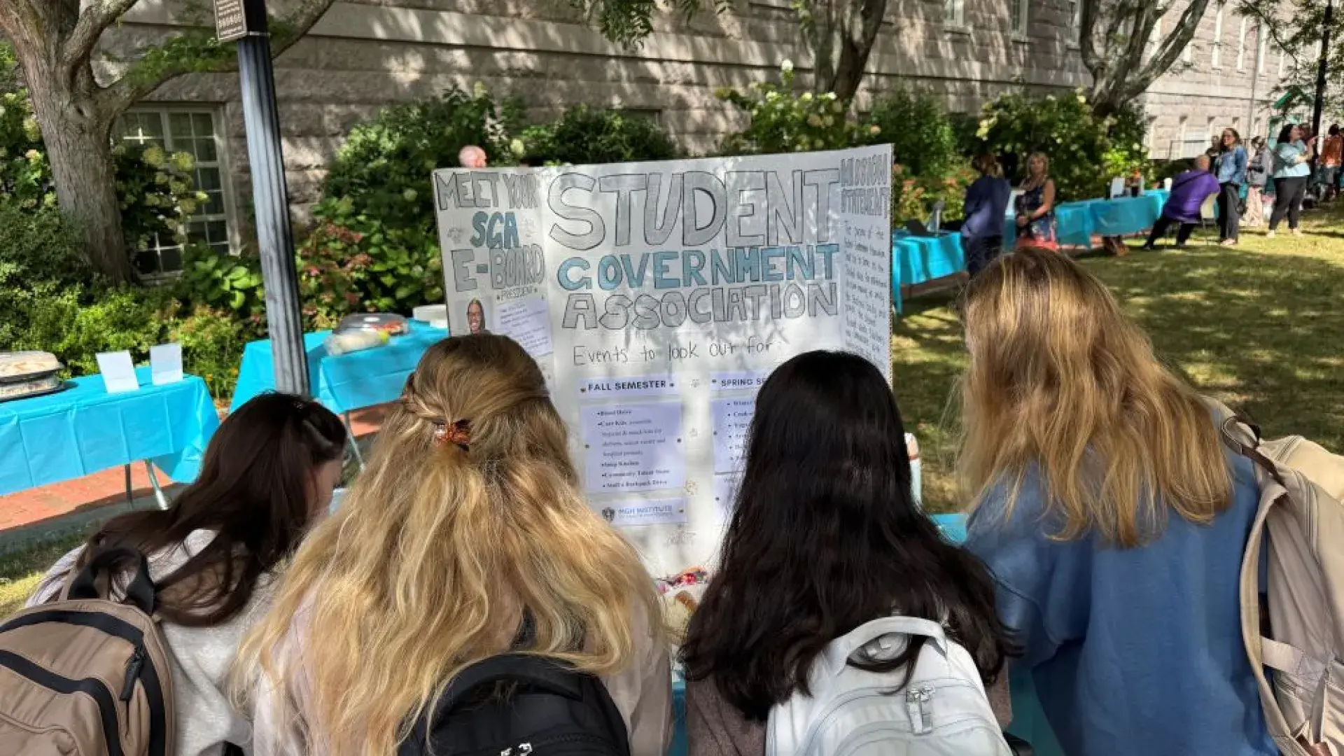 the back of 4 girls' heads reading a poster board