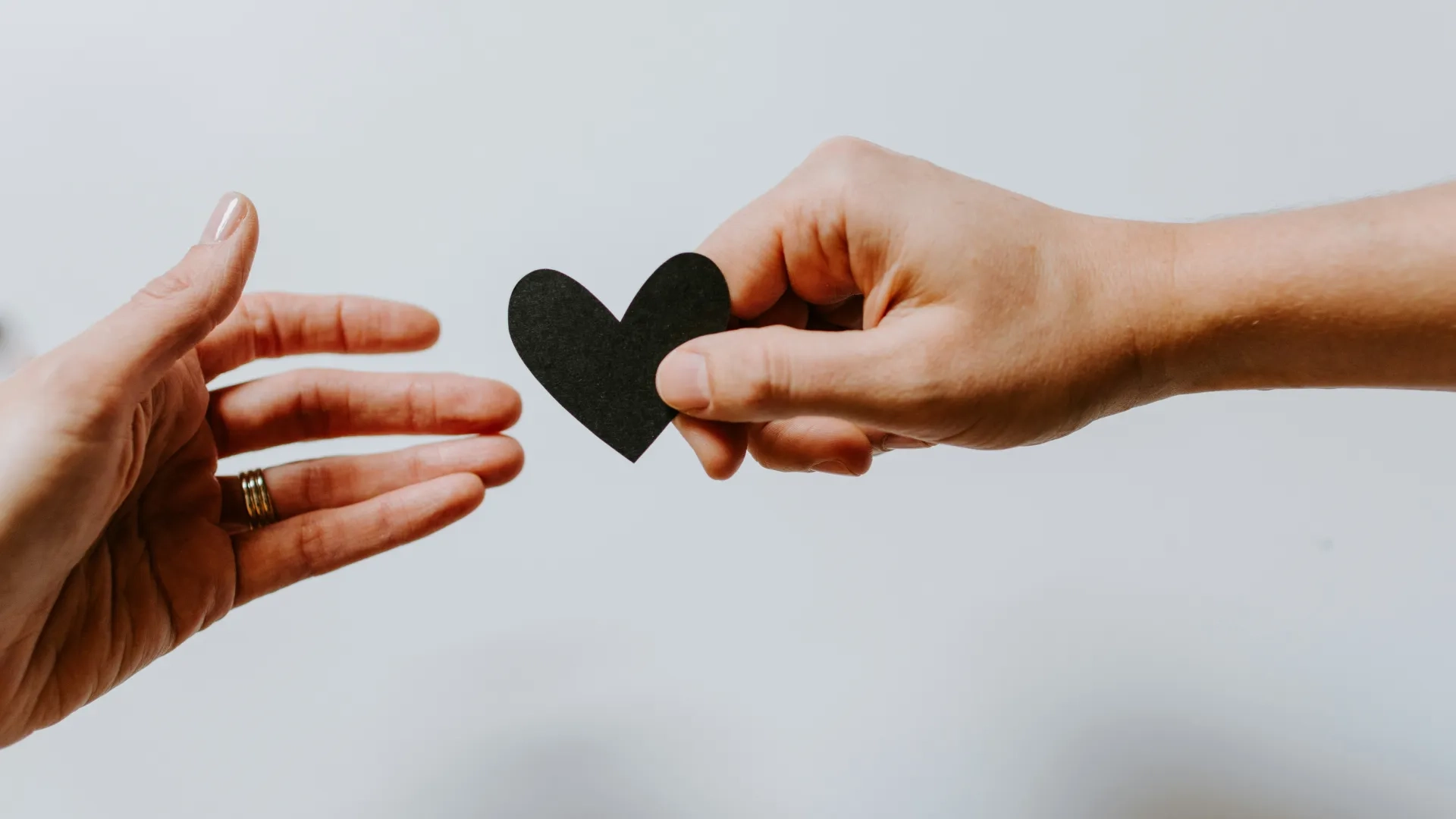 one hand handing a heart to another