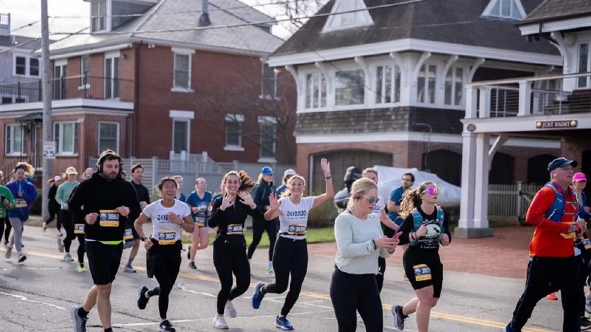 People running a race with two women in the center raising their hands