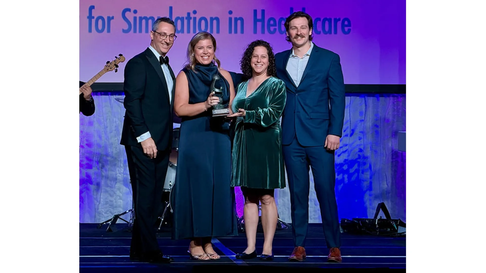 Four people pose with an award on a stage