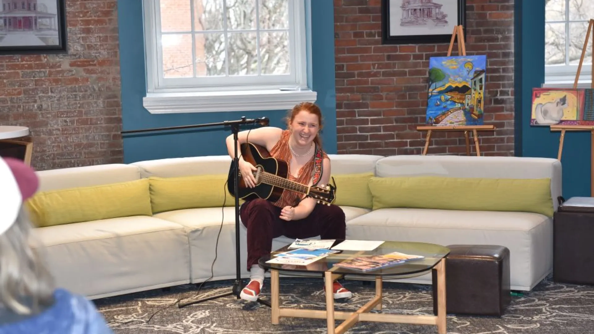 girl with a guitar sings on a couch