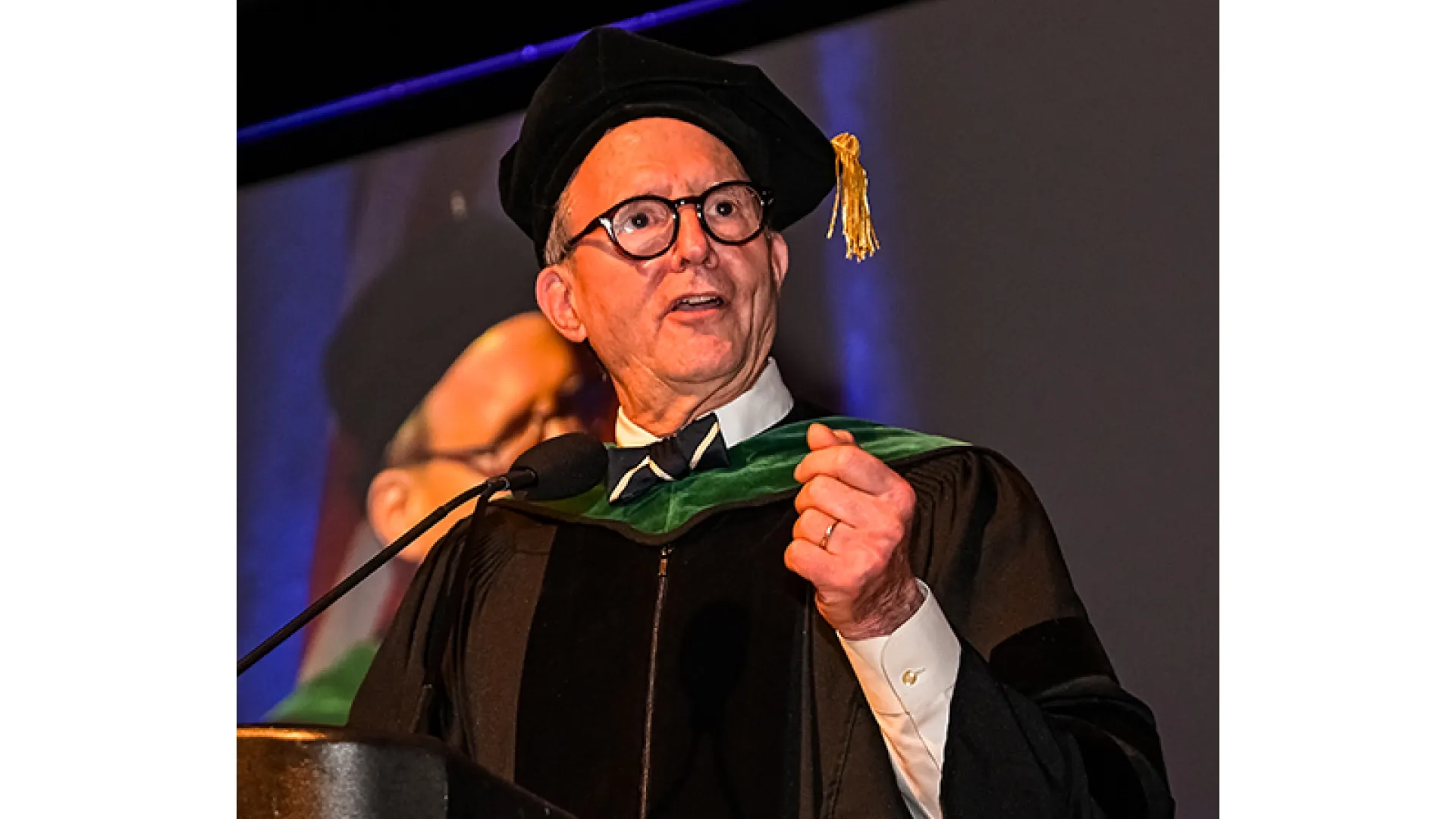 A man behind a microphone at a commencement
