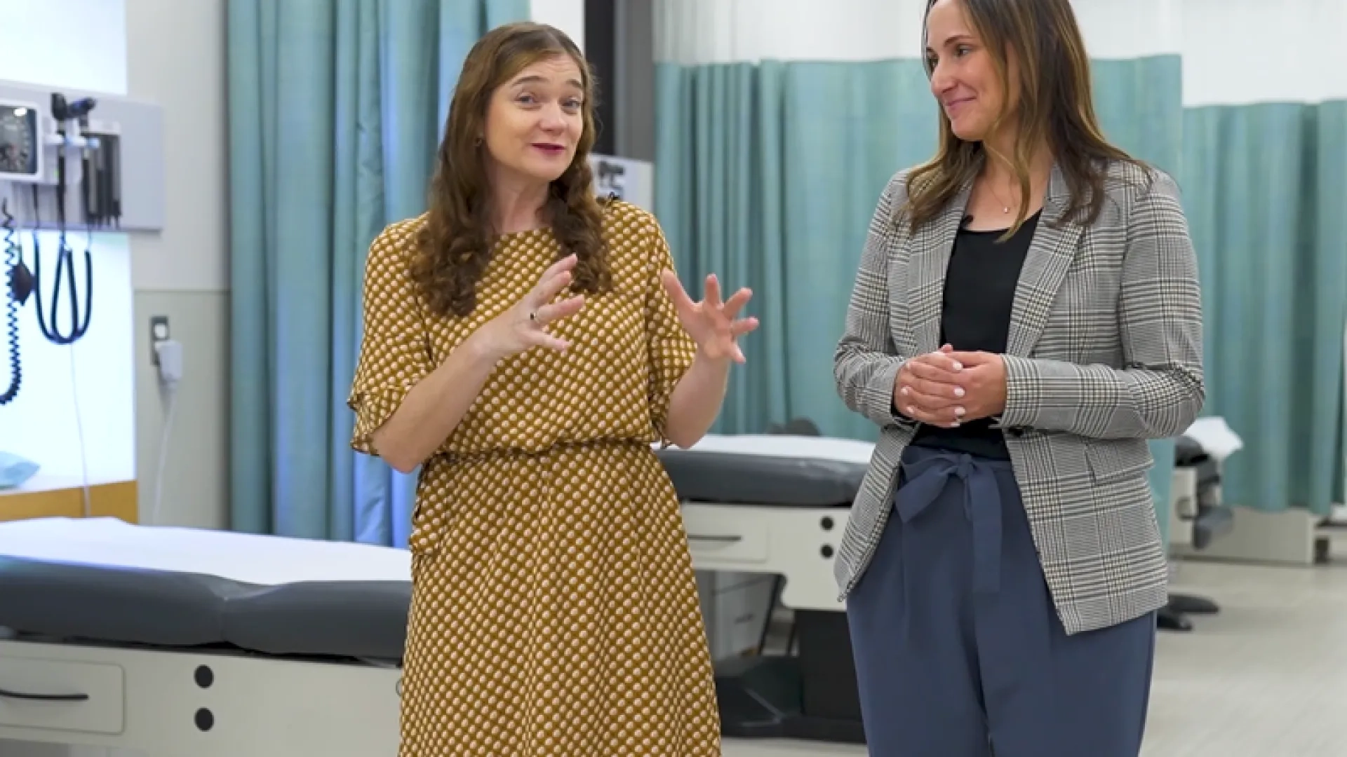 two women stand in a clinical space and talk about the AACN domains