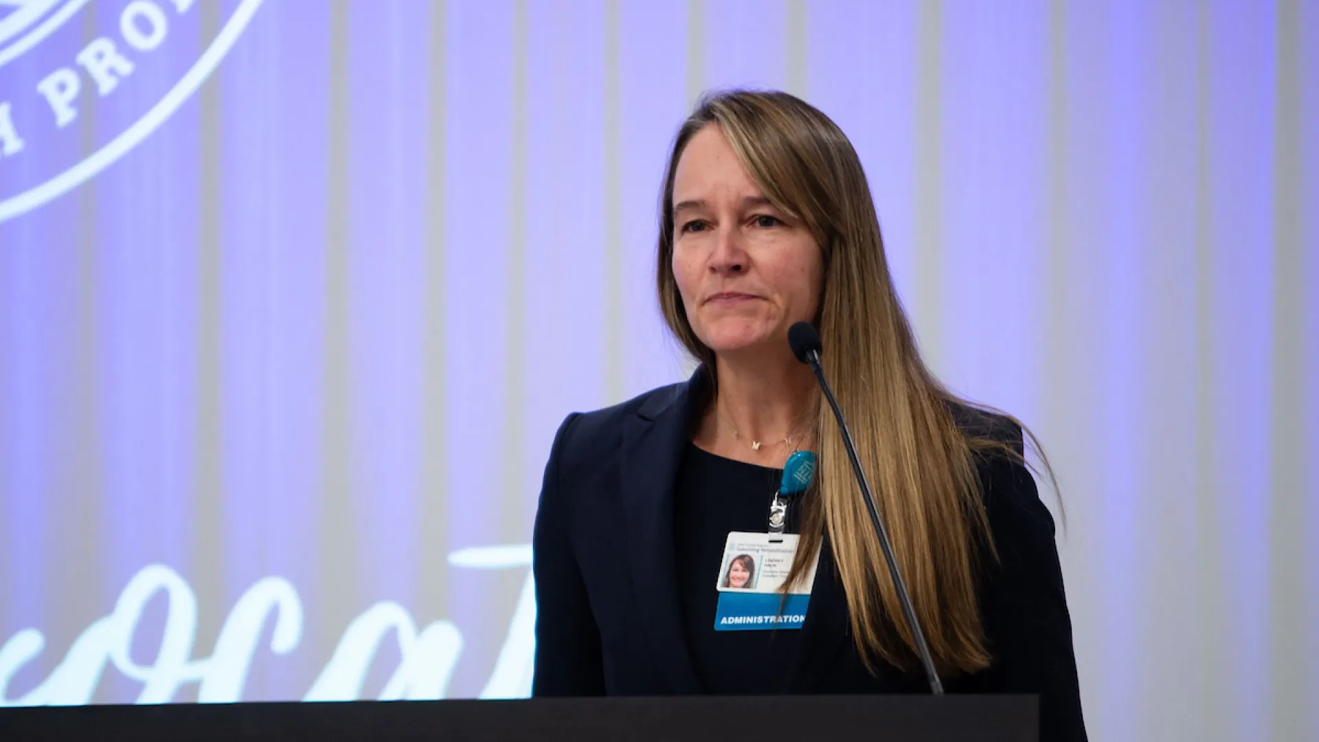 woman standing at podium with long hair
