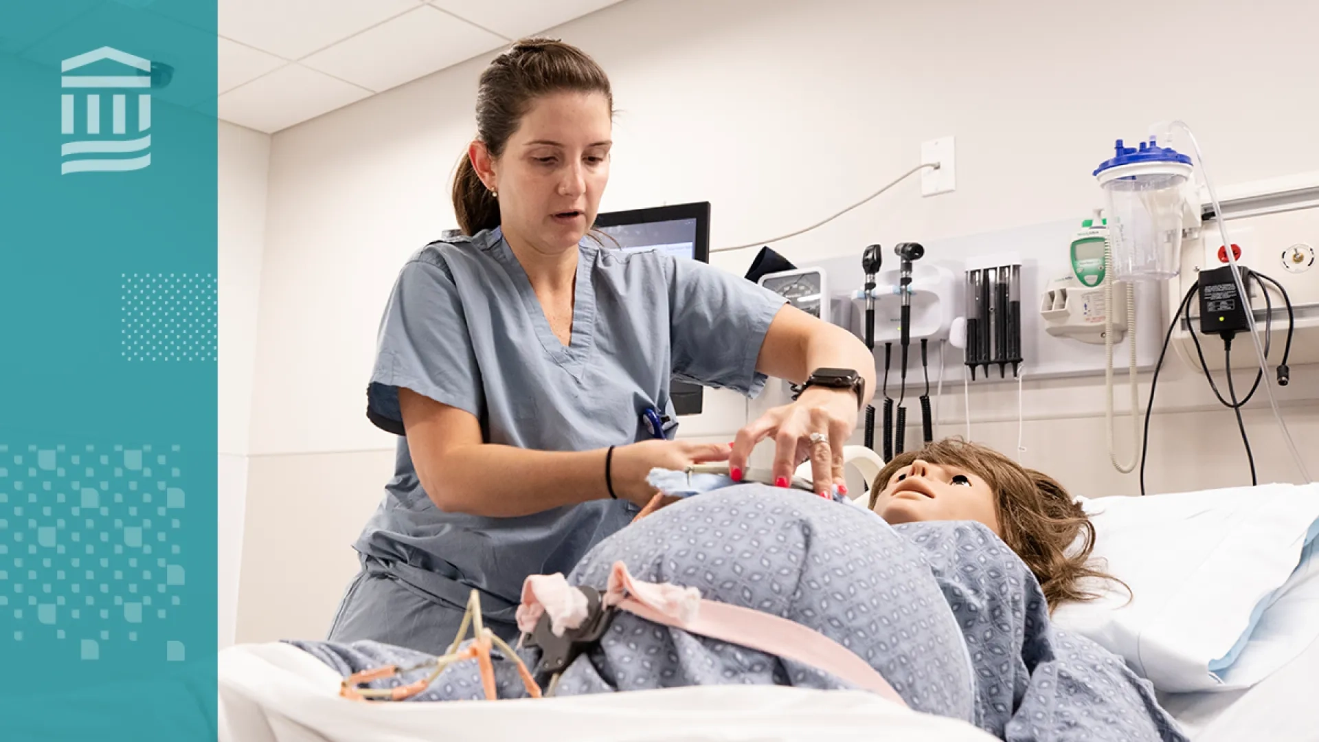 woman in scrubs adjusts a strap on a pregnant manikin in a hospital bed