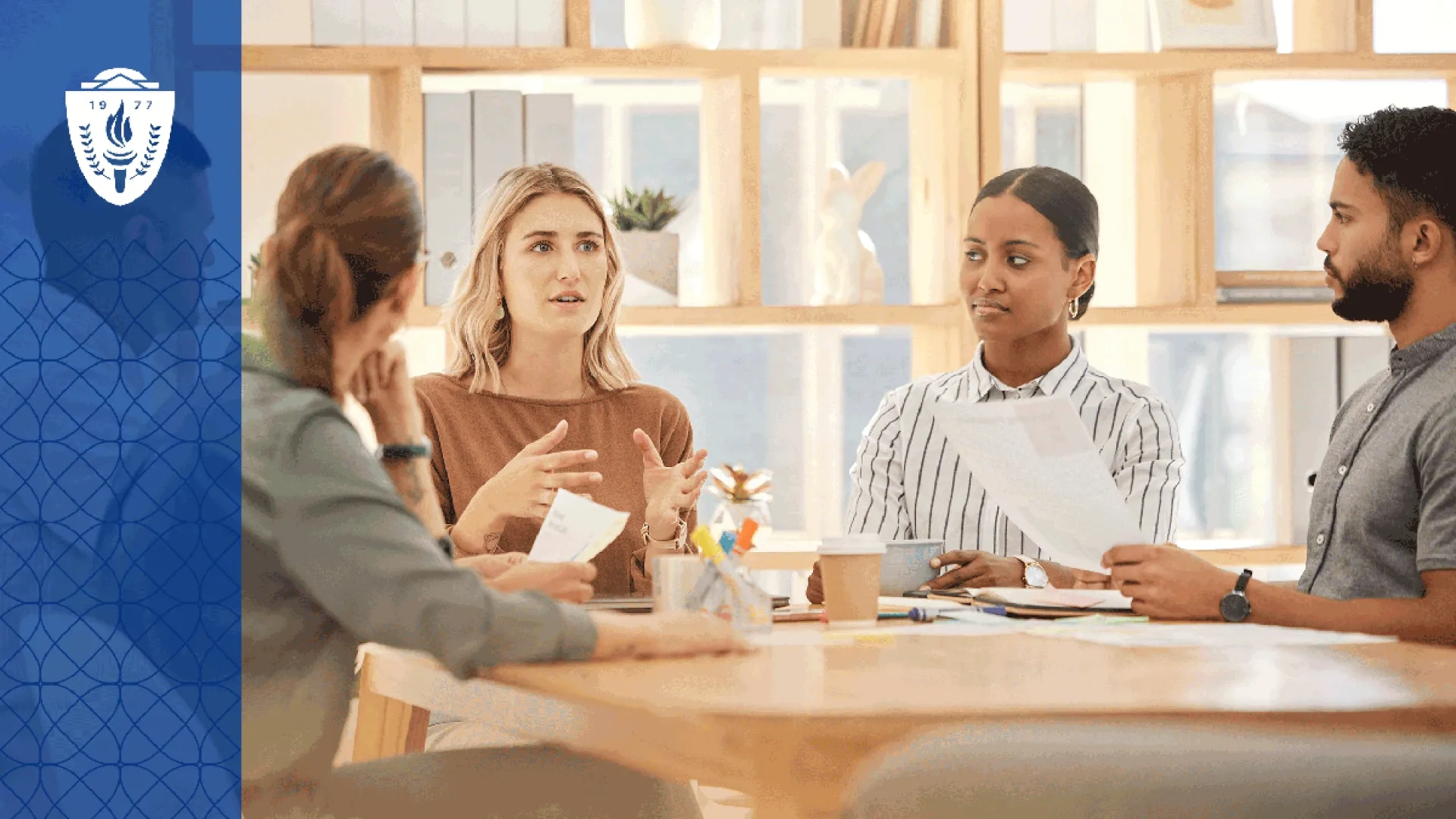 A workplace team gathers around a conference table while one person leads a discussion on inclusive practices and collaboration. 