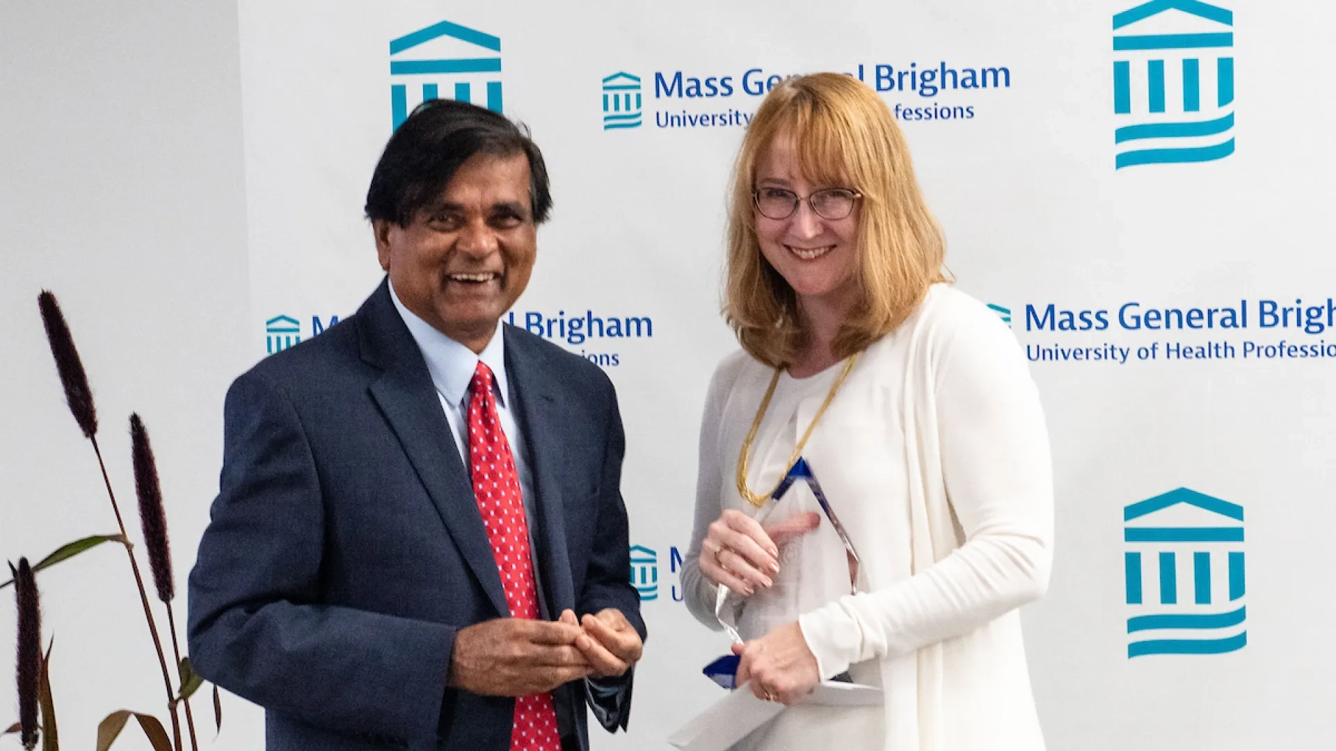 man standing to the left of a woman holding a glass award