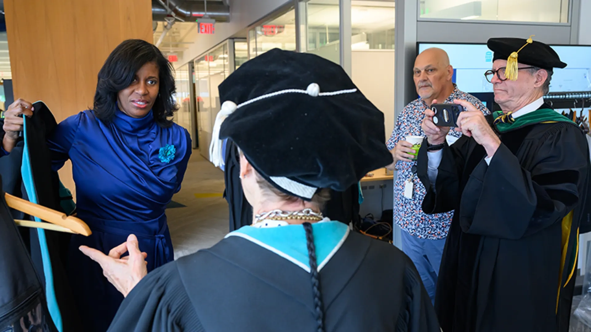 Deborah Jones puts on regalia before the Inauguration ceremony while Dr. John Herman takes a photo