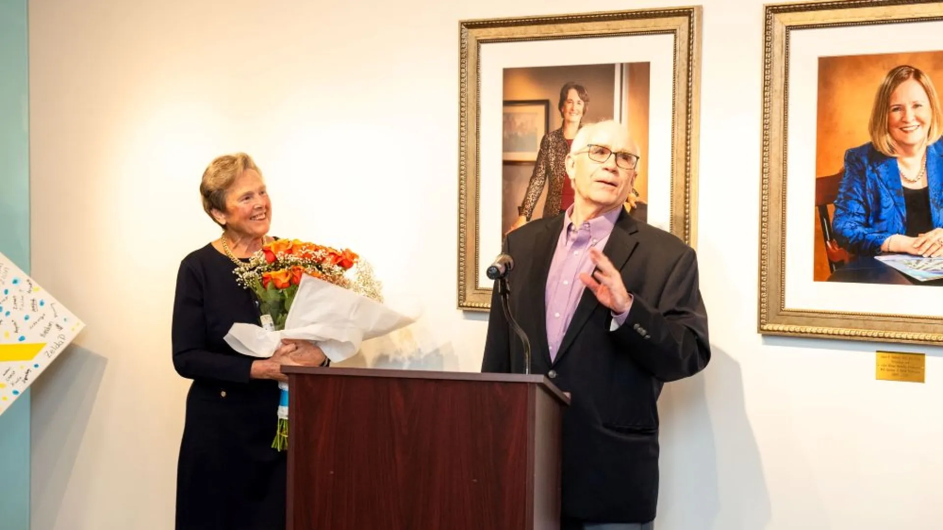 woman standing with flowers next to man behind podium 