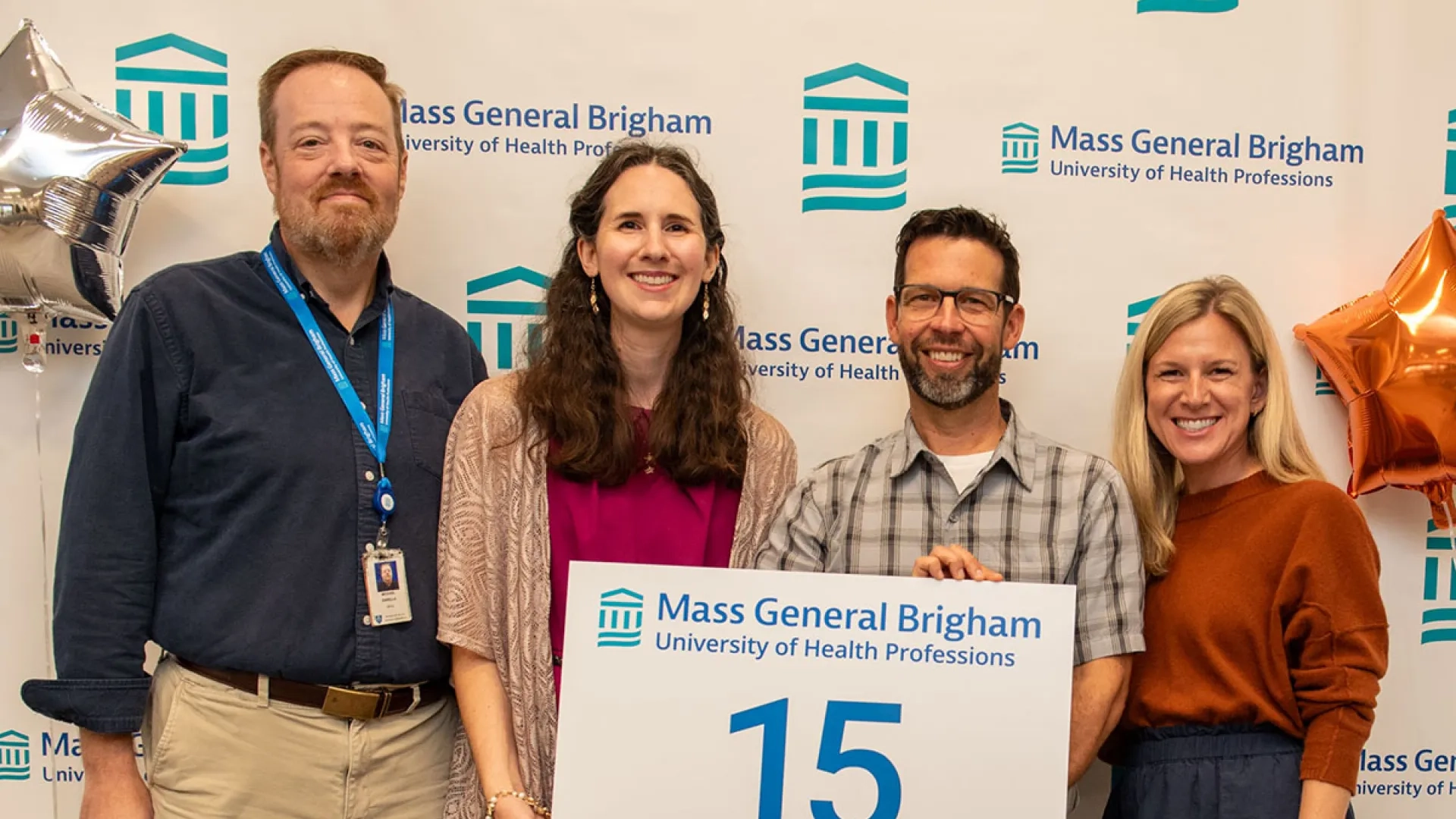 Four people stand with a sign with the number 15 on it 