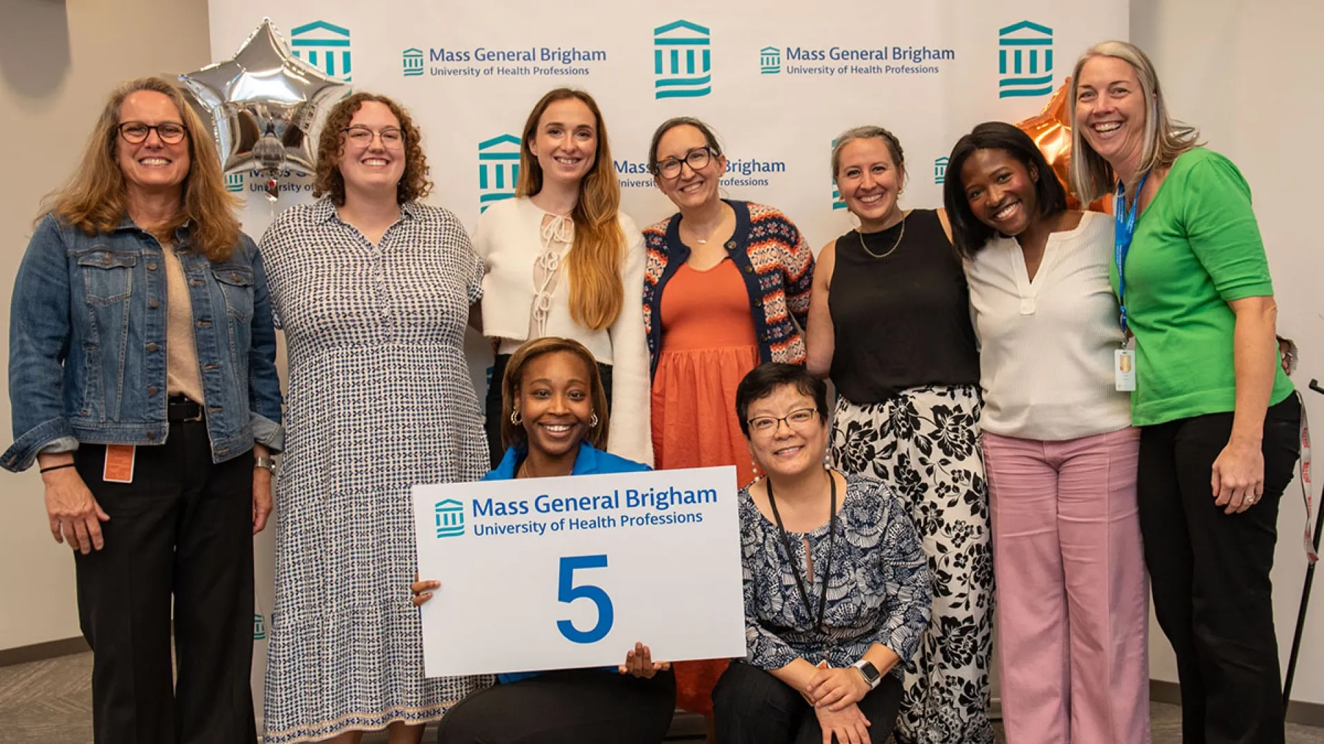 Employees pose with a sign that has the number 5