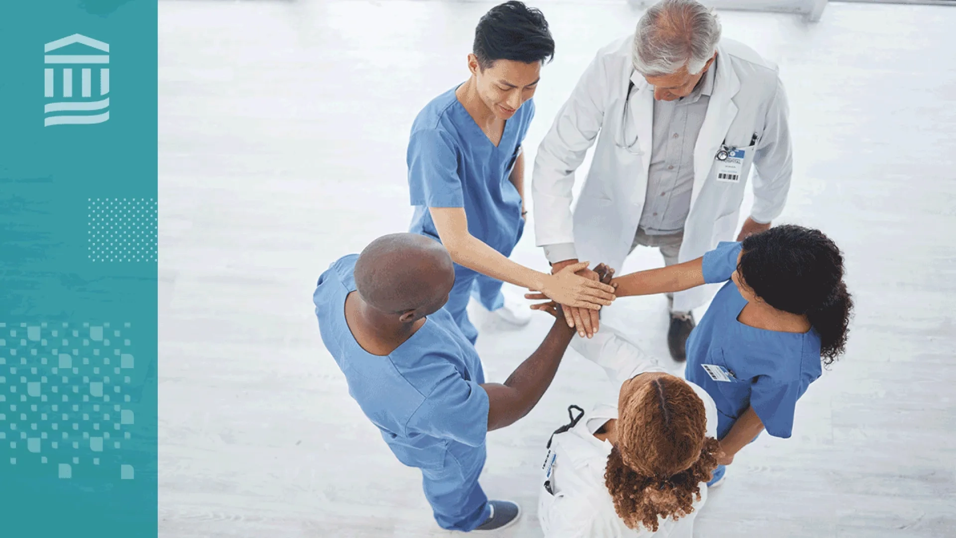 Members of a healthcare team stand in a circle with their hands stacked together in a show of teamwork.