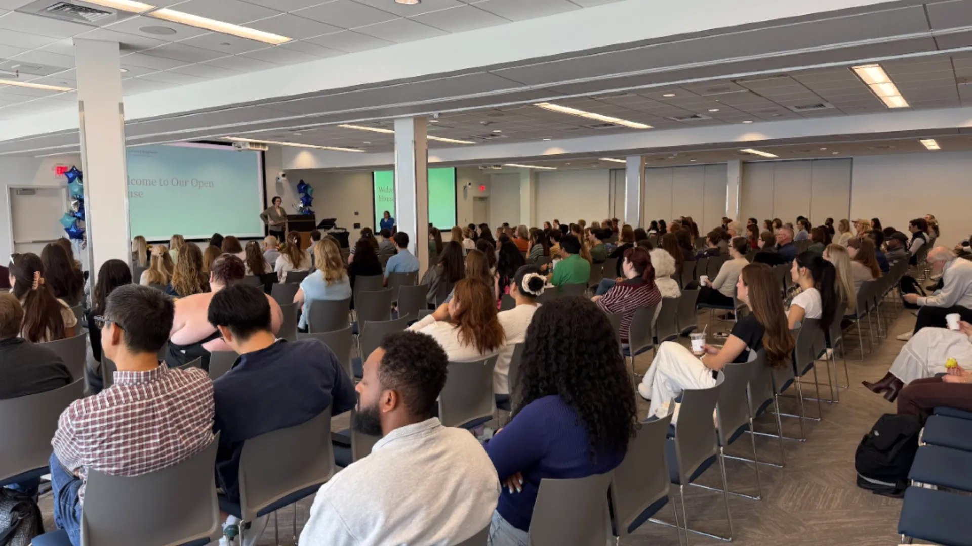 photo of large room with rows of people sitting in chairs