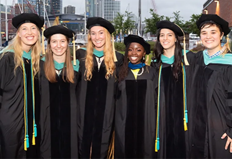 group smiles for the camera with their black graduation robes