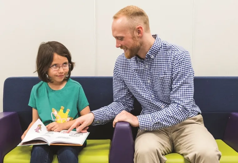 A literacy coach in the Literacy and Language Certificate Program helps a young student with reading comprehension. The program focuses on evidence-based literacy instruction and advanced literacy strategies, preparing educators for reading specialist certification and literacy leadership training.