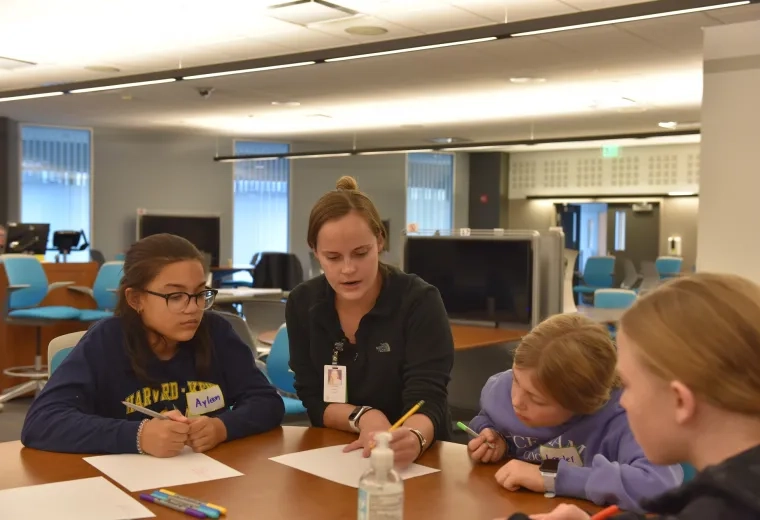 Fifth-grader, Ayleen (left) watches nursing student Lauren O'Neil (center). They're joined by two other Harvard-Kent students
