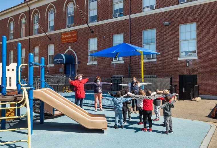children and adults do exercises in a playground