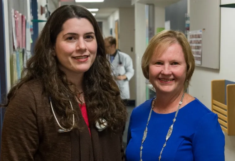 two women stand in a hallway together