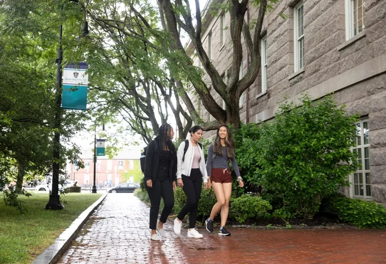 diverse women walking on a brick path through campus
