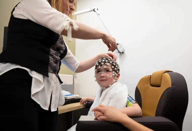 yael places a cap made of tiny white circles on a little boy's head