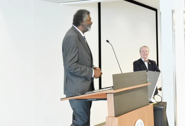 Black man in grey suit speaks