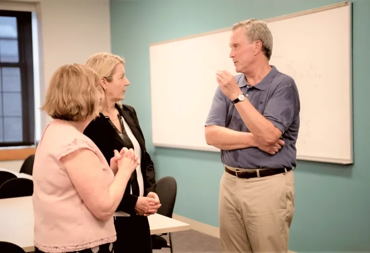 Two women talking to a man in a room