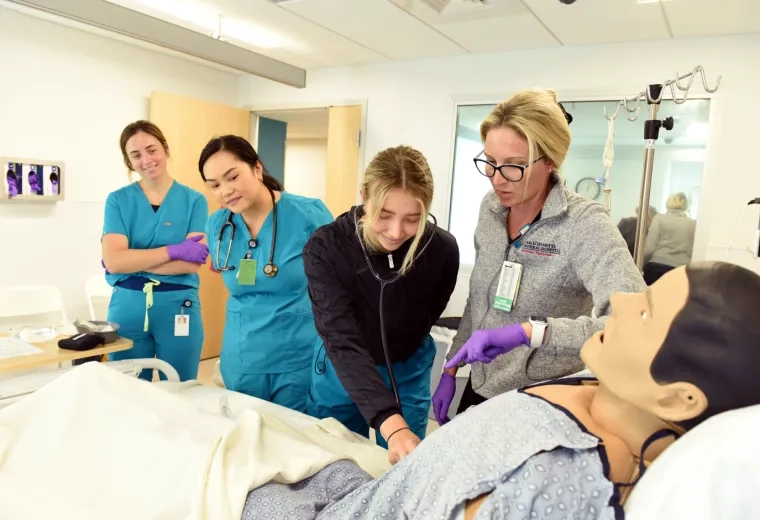 Nursing sim lab with instructor, students, and manikin