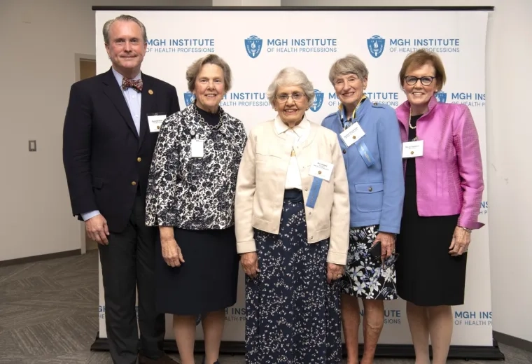 Five people smiling and standing in front of a banner