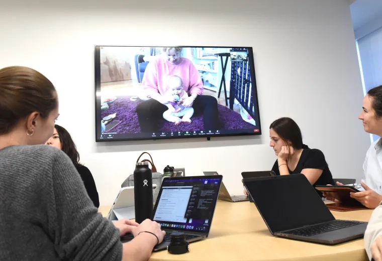 People sitting around a table watching a wall monitor