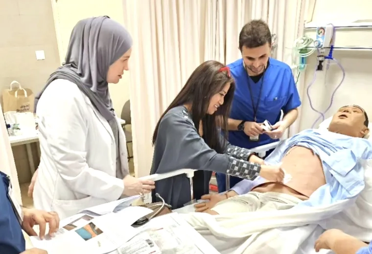 People working with a manikin in a hospital bed