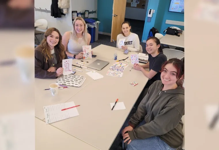 people sitting around a table smiling with cards and markers