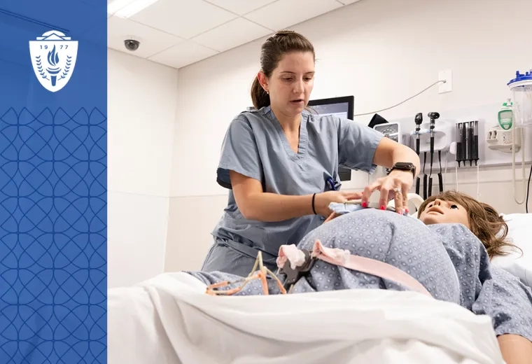 woman in scrubs adjusts a strap on a pregnant manikin in a hospital bed