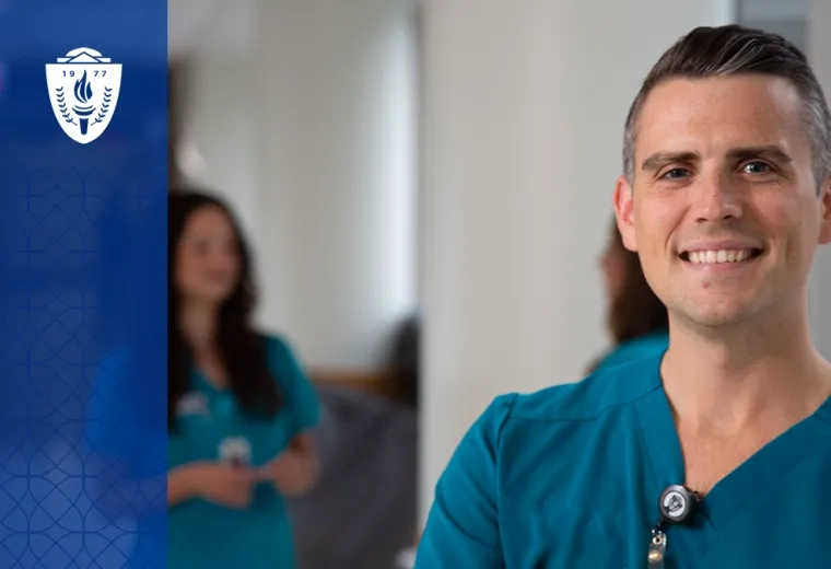a man smiles in nursing scrubs in the hallway of a hospital