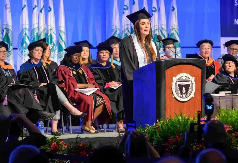 Woman in cap and gown talking at podium