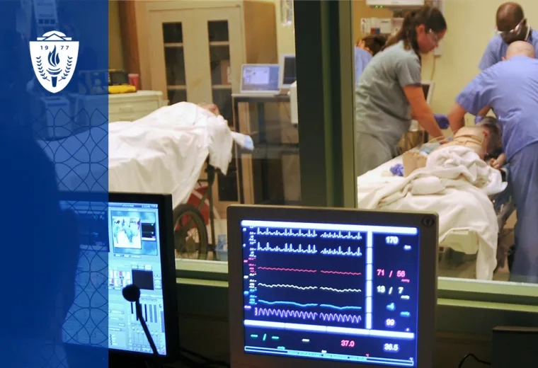 a computer screen with lines monitoring vitals like heartbeats is in front of a window where people in scrubs are working on a manikin in a hospital bed
