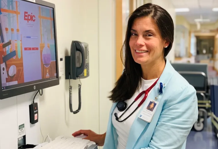 woman standing at a computer in a hospital hallway