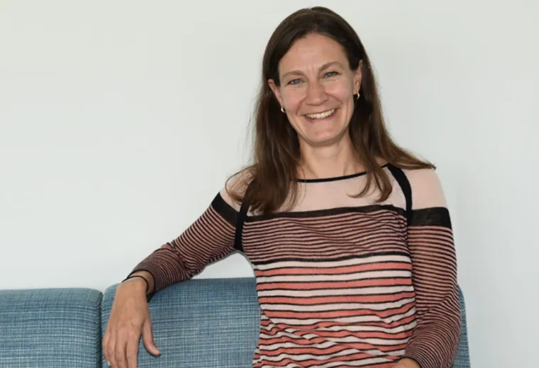 A woman sits on a couch facing the camera