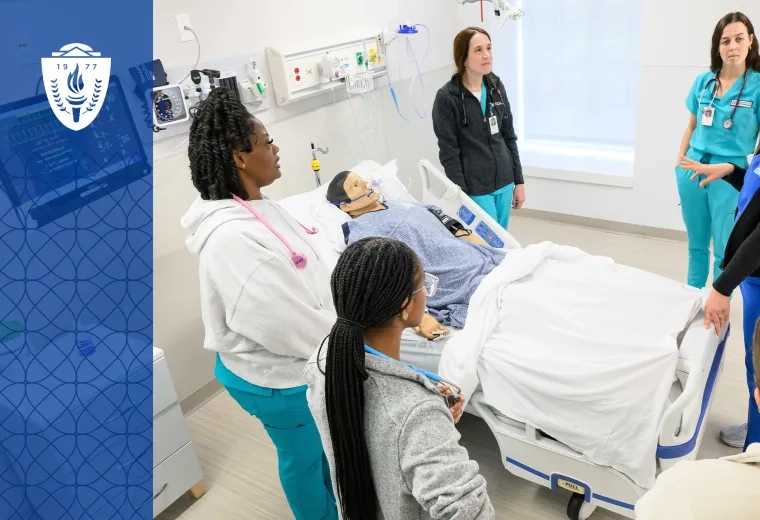 Education in the Health Professions is changing, here we see a faculty member in scrubs surrounded by five students in scrubs around a hospital bed with a manikin