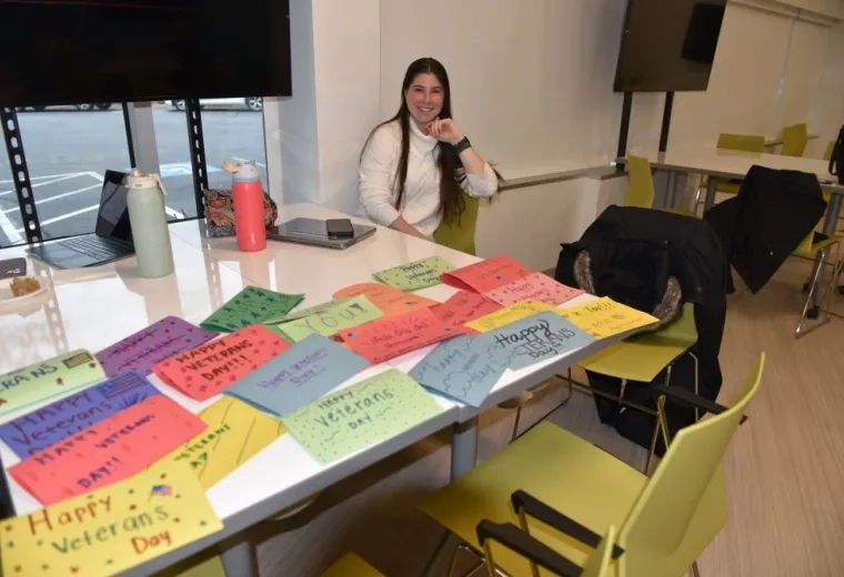 A woman sits at a table with homemade cards thanking Veterans