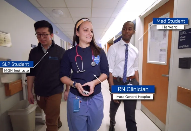 3 people walk down a hallway together, noted to be a SLP Student from Mass General Brigham University, an RN Clinician from MGH, and a med student from Harvard